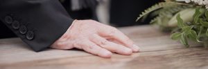 Hand on top of a casket at a funeral