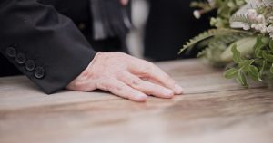 Hand on top of a casket at a funeral